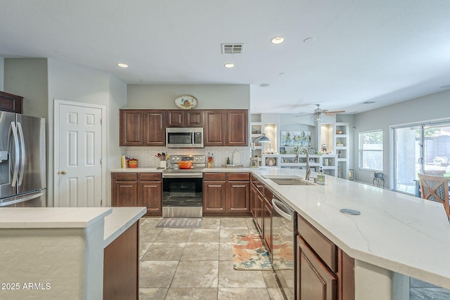 15848 W Calavar Rd, Surprise, AZ 85379 - kitchen with stainless steel appliances, a sink, a peninsula, light stone countertops, and ceiling fan