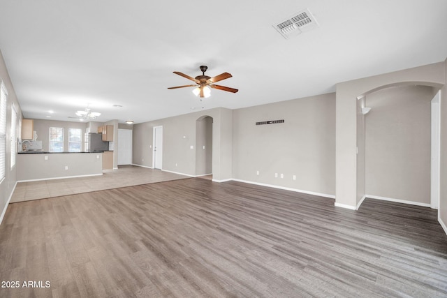 unfurnished living room featuring ceiling fan, sink, and light wood-type flooring