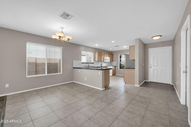 kitchen featuring sink, backsplash, a chandelier, range, and kitchen peninsula