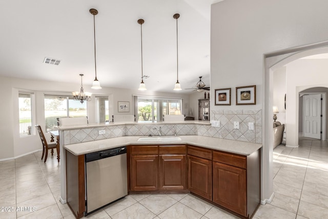 kitchen with arched walkways, a sink, light countertops, dishwasher, and backsplash