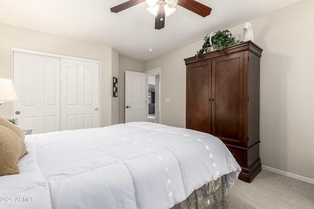 bedroom with a closet, light colored carpet, a ceiling fan, and baseboards