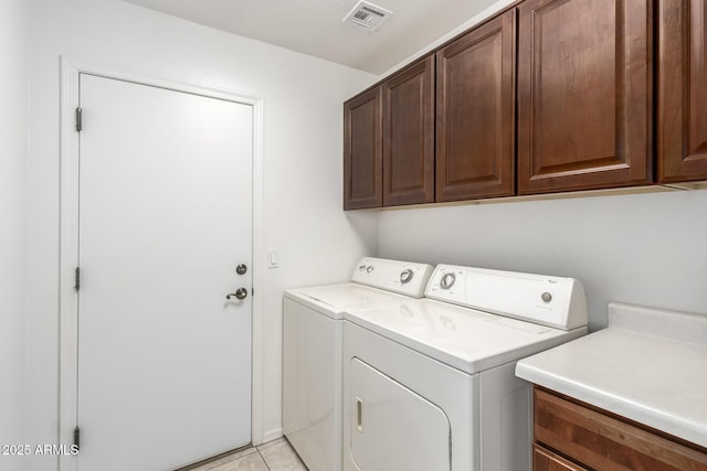 washroom featuring visible vents, cabinet space, light tile patterned flooring, and washer and clothes dryer