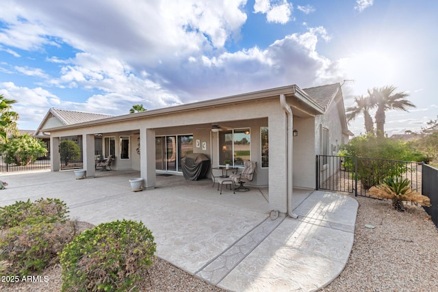 back of house with stucco siding, a patio, a ceiling fan, and fence