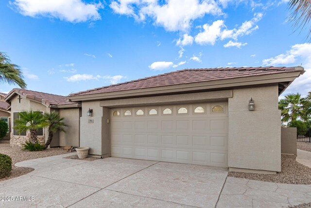 view of front of property with stucco siding, a garage, driveway, and a tiled roof