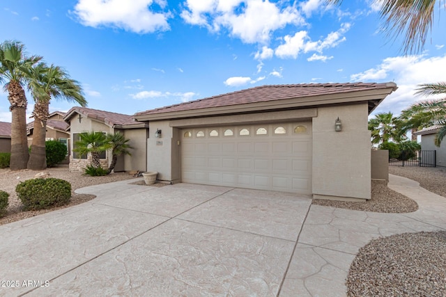 view of front of house with fence, an attached garage, stucco siding, concrete driveway, and a tiled roof