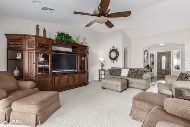 living room with a ceiling fan, visible vents, lofted ceiling, arched walkways, and light colored carpet