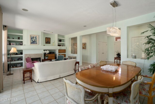 16158 W Copper Point Ln, Surprise, AZ 85374 - dining room with built in shelves, light tile patterned floors, a chandelier, and a fireplace