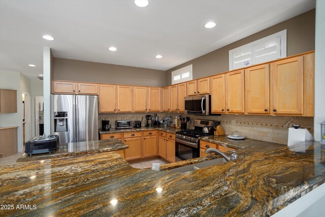 16158 W Copper Point Ln, Surprise, AZ 85374 - kitchen with appliances with stainless steel finishes, decorative backsplash, dark stone counters, a sink, and recessed lighting