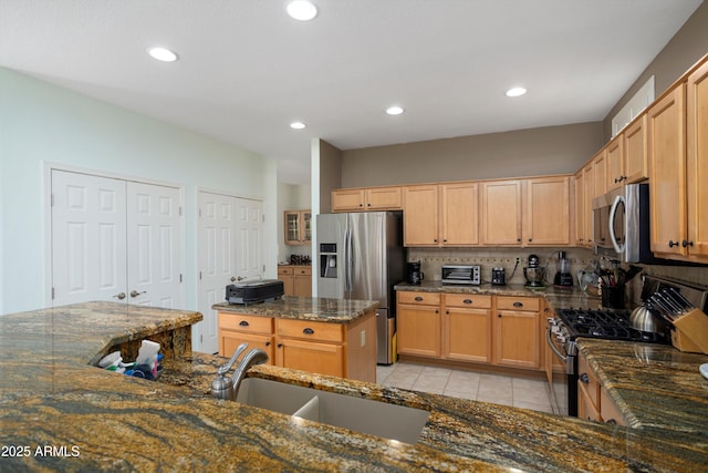 16158 W Copper Point Ln, Surprise, AZ 85374 - kitchen featuring stainless steel appliances, a sink, light tile patterned flooring, dark stone counters, and recessed lighting