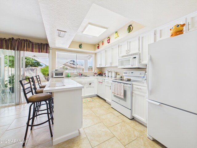 7676 W Sells Dr, Phoenix, AZ 85033 - kitchen with a kitchen bar, light tile patterned flooring, white appliances, and white cabinets