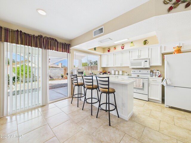 7676 W Sells Dr, Phoenix, AZ 85033 - kitchen featuring visible vents, white cabinets, light countertops, a kitchen breakfast bar, and white appliances