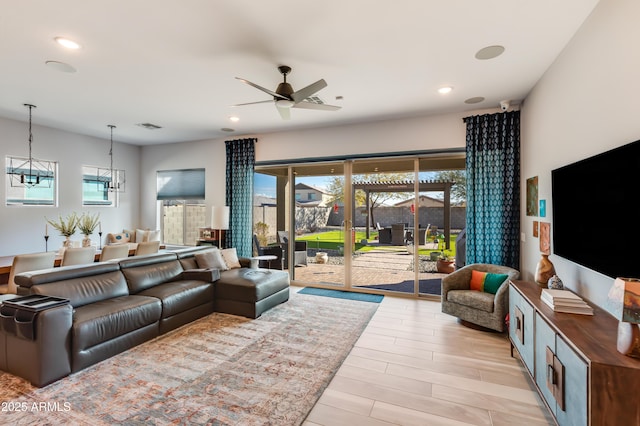 living room featuring ceiling fan with notable chandelier and a wealth of natural light