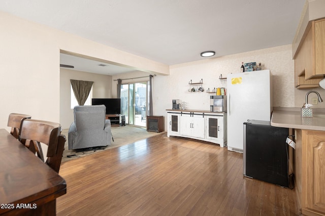 kitchen featuring hardwood / wood-style floors, freestanding refrigerator, light brown cabinetry, light countertops, and open floor plan