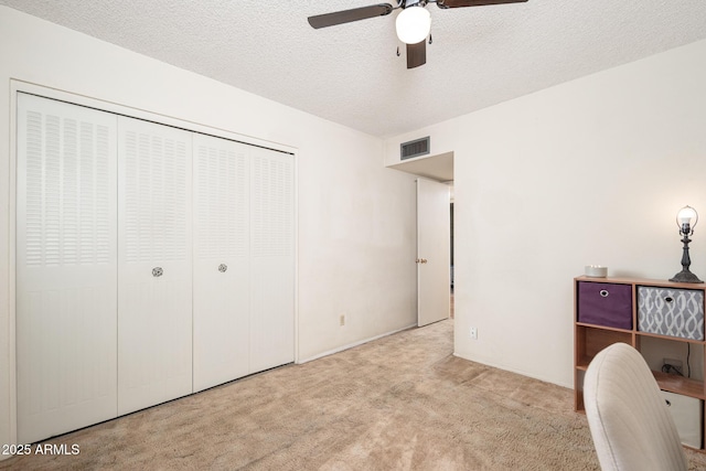 unfurnished office featuring ceiling fan, carpet, visible vents, and a textured ceiling