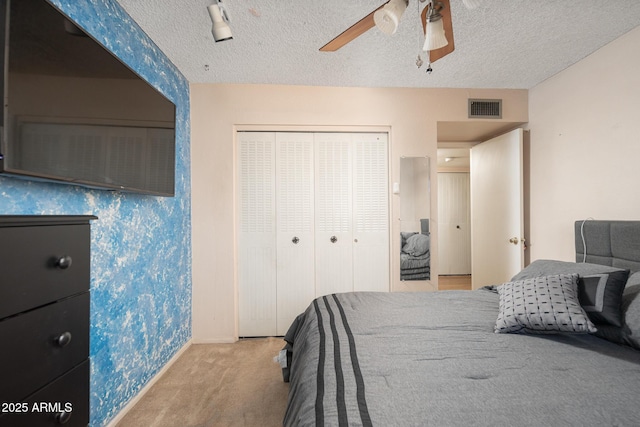 carpeted bedroom with a closet, visible vents, a textured ceiling, and a ceiling fan