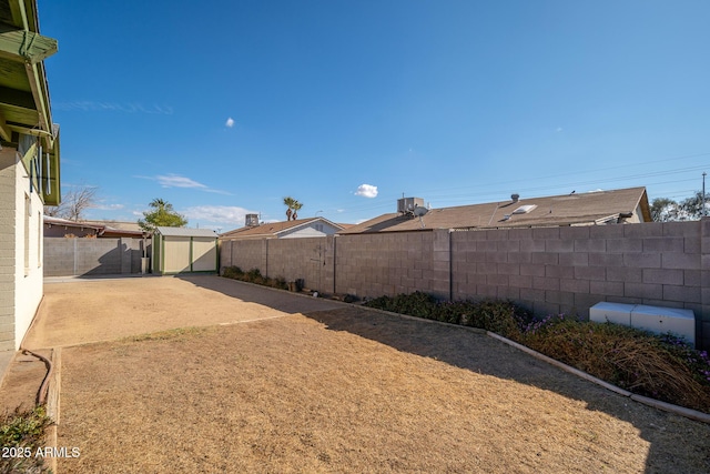 view of yard with a fenced backyard, a patio, an outdoor structure, and a shed