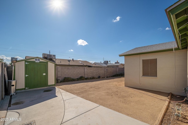 view of yard with central air condition unit, a fenced backyard, a storage shed, an outdoor structure, and a patio area