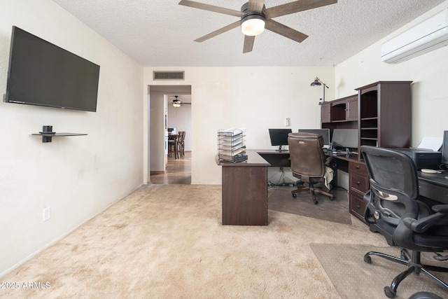 office area featuring visible vents, light carpet, an AC wall unit, a textured ceiling, and ceiling fan