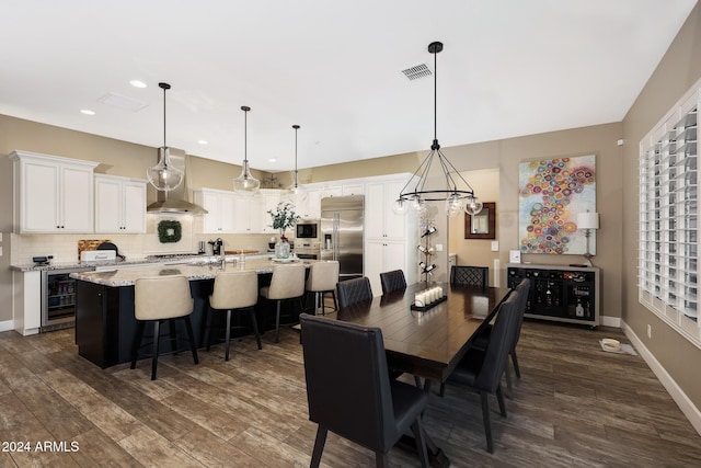 dining area with dark wood-type flooring, beverage cooler, and a chandelier