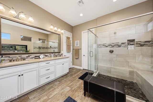 bathroom featuring backsplash, walk in shower, and vanity