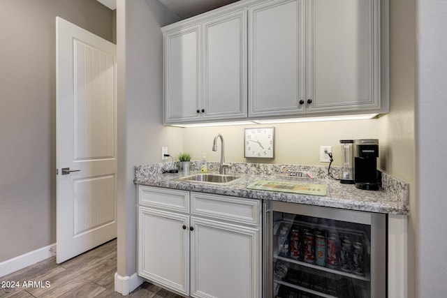 bar featuring wine cooler, sink, white cabinetry, light hardwood / wood-style flooring, and light stone counters