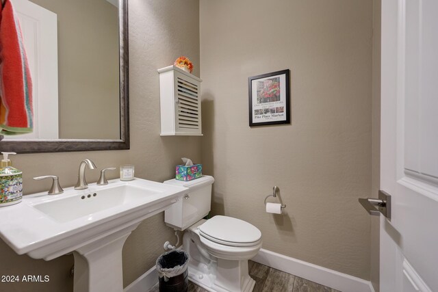 bathroom with toilet, wood-type flooring, and sink