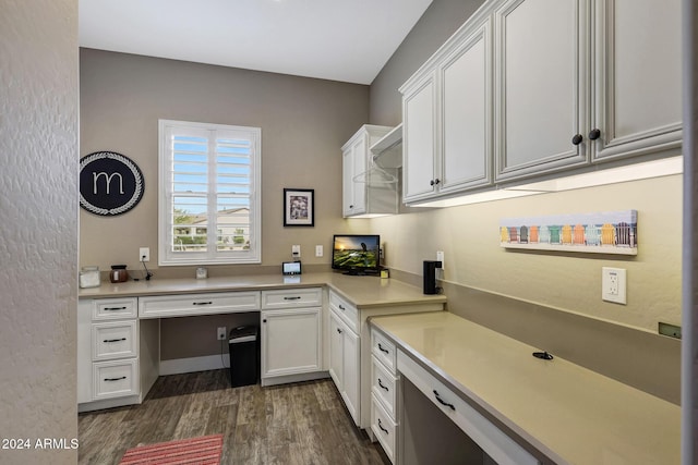 home office with dark hardwood / wood-style flooring and built in desk