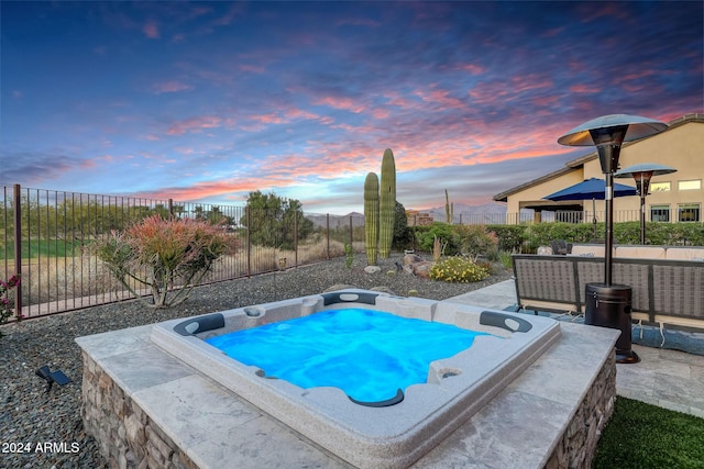 pool at dusk featuring an outdoor hot tub