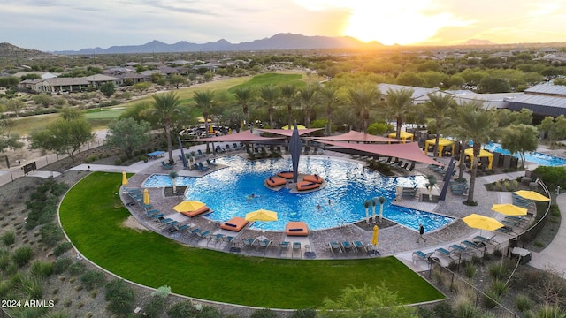 pool at dusk featuring a mountain view and a yard