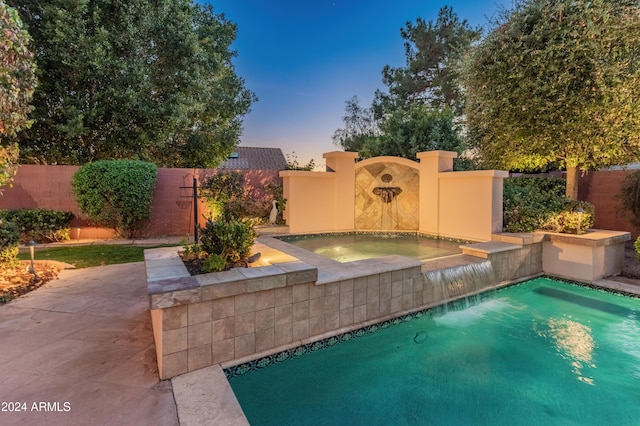 pool at dusk featuring an in ground hot tub