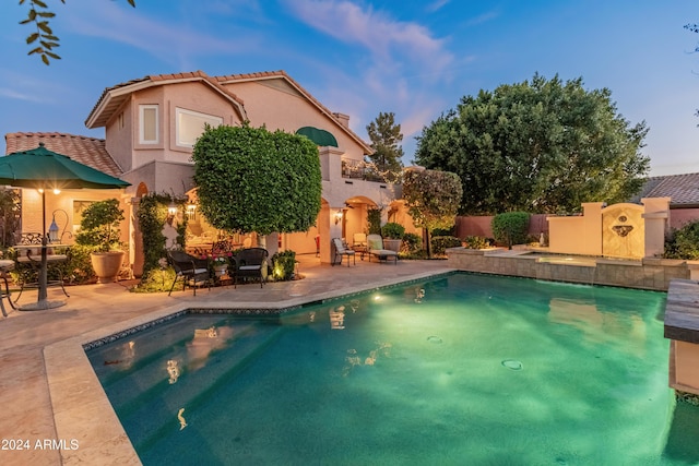 pool at dusk with a patio