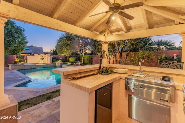 pool at dusk with a gazebo, ceiling fan, and area for grilling