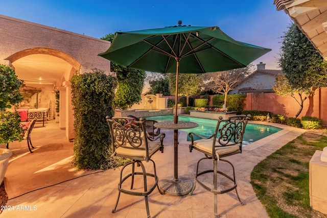 pool at dusk featuring a patio