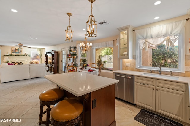 kitchen featuring sink, a kitchen breakfast bar, stainless steel dishwasher, a kitchen island, and ceiling fan with notable chandelier