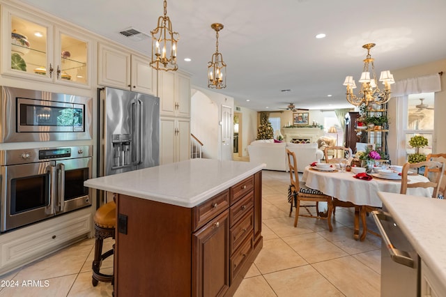 kitchen with appliances with stainless steel finishes, ceiling fan with notable chandelier, decorative light fixtures, and light tile patterned flooring