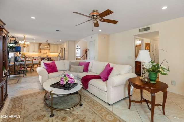 tiled living room featuring ceiling fan with notable chandelier