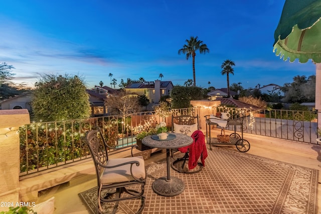 patio terrace at dusk featuring a balcony