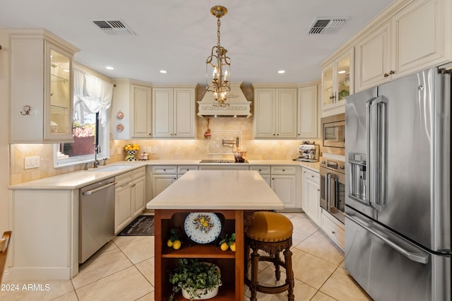 kitchen featuring backsplash, a kitchen island, stainless steel appliances, and cream cabinetry