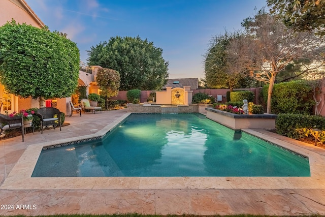 pool at dusk featuring a patio