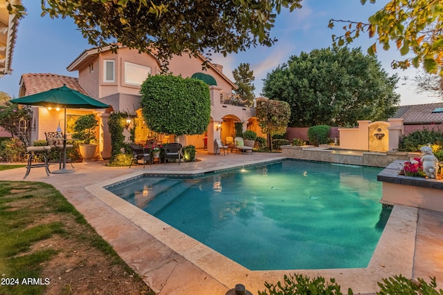 pool at dusk featuring a patio