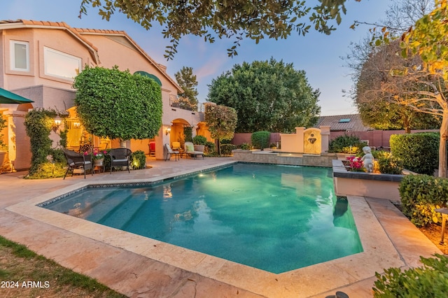 pool at dusk with a patio area