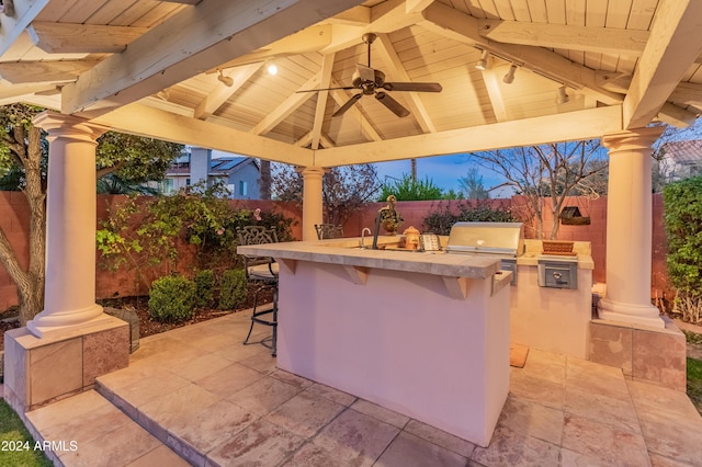 view of patio / terrace with ceiling fan, exterior kitchen, a gazebo, a bar, and a grill