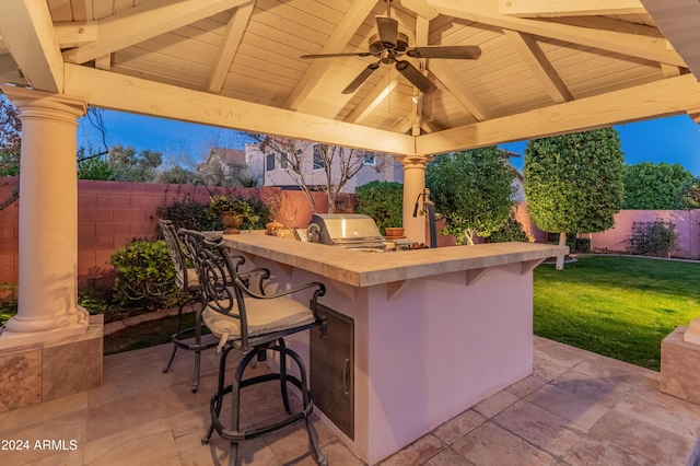 view of patio featuring ceiling fan, an outdoor kitchen, a grill, a gazebo, and a bar