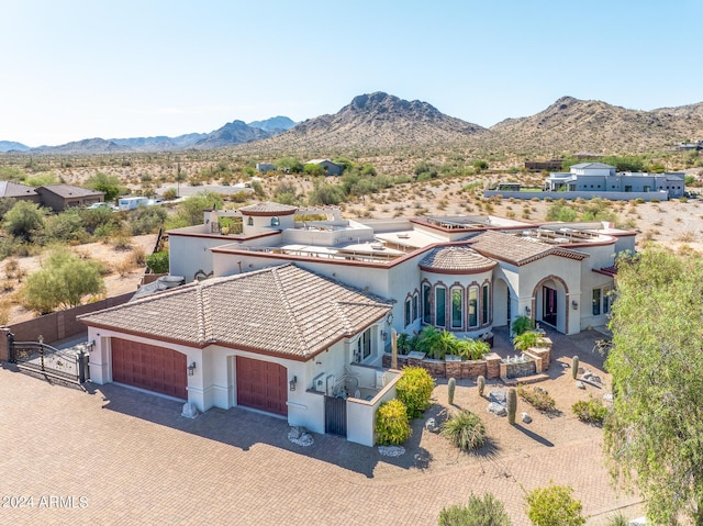 view of front facade with a tile roof, an attached garage, decorative driveway, a mountain view, and stucco siding