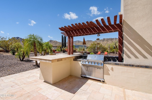 view of patio / terrace featuring an outdoor kitchen, fence, a mountain view, and a pergola