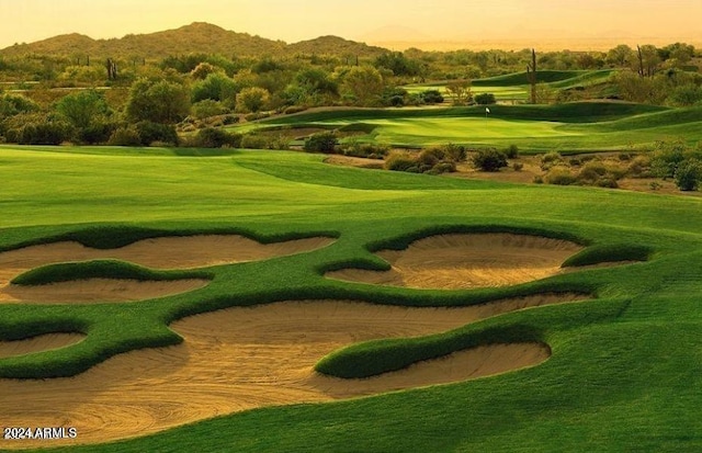 view of property's community with a mountain view, golf course view, and a lawn