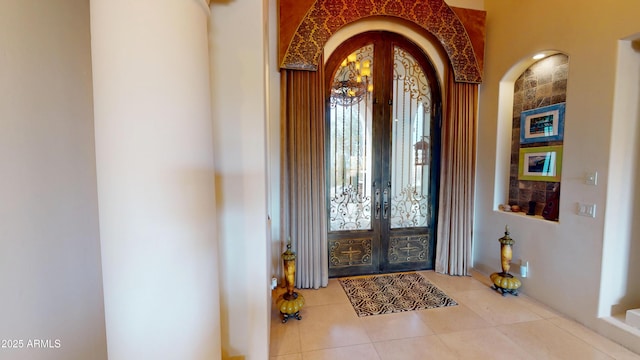 foyer entrance with light tile patterned floors, arched walkways, and french doors