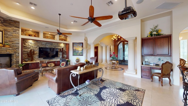 living area with ornate columns, visible vents, arched walkways, and a raised ceiling