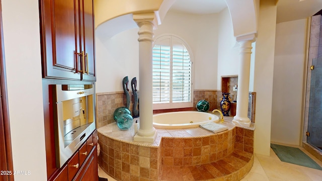 bathroom featuring a shower stall, tile patterned floors, a garden tub, and ornate columns