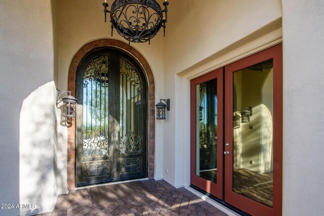 tiled foyer entrance with a chandelier, a tray ceiling, and ornate columns